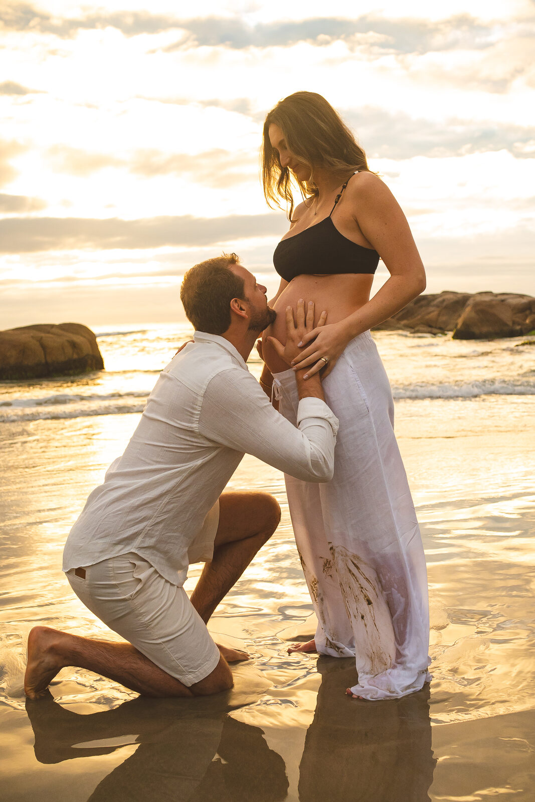 Ele ajoelhado na água beijando a barriga